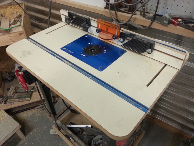 A tight picture of the top of the router table showing slots for clamping  jigs, fence, and anti-kickback devices.